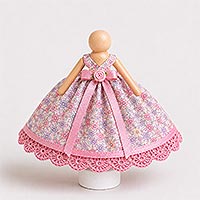 Floral fabric bodice straps attached over the shoulders of a doll pin and covered by a pink satin ribbon waistband and bow, illustrating the proper placement and alignment of the dress straps for a handmade doll pin doll.
